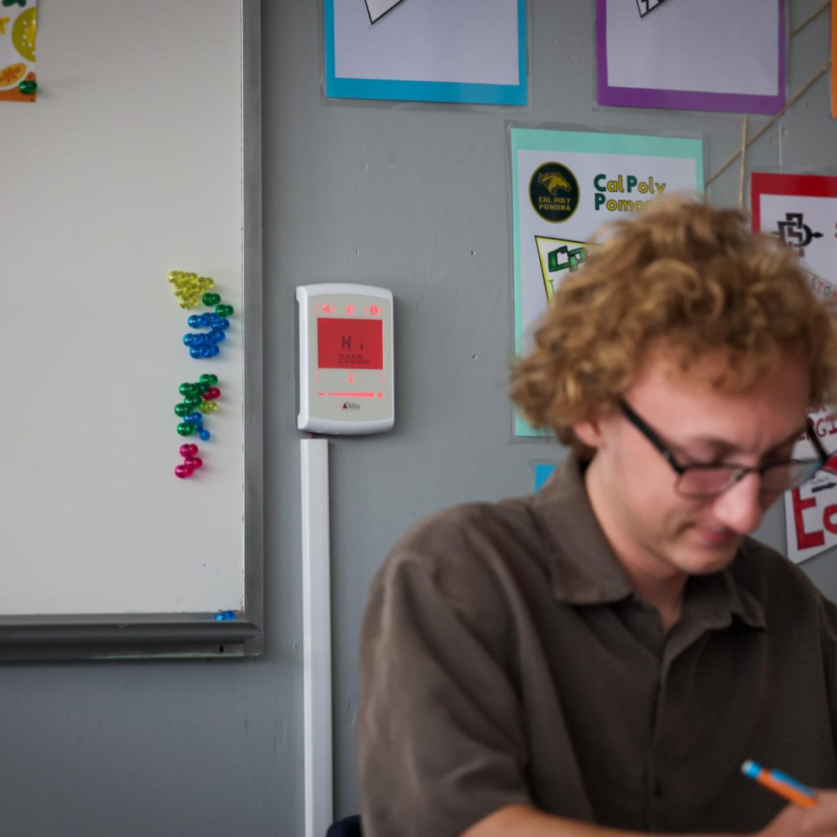 Senior Alex Swanson reads A Doll's House, a play by Henrik Ibsen, in English teacher Mrs. Kelly Abram’s classroom while the newly installed carbon dioxide monitor demonstrates a CO2 level higher than 1500 ppm. (The Lancer/ Alan Ko)