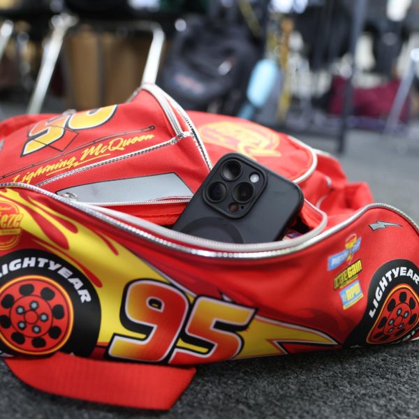 iPhone 15 sits in senior Alan Ko's Lighting McQueen backpack in the journalism classroom (I-4) after Thousand Oaks High School becomes the first high school in the Conejo Valley Unified School District to implement a phone policy. Phones and earbuds are not allowed to be seen by a teacher during instructional time. (The Lancer/ Alan Ko) 